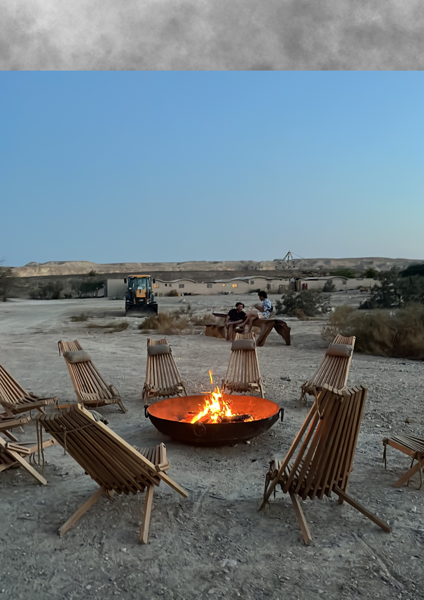 Desert fire circle with wooden chairs at dusk.